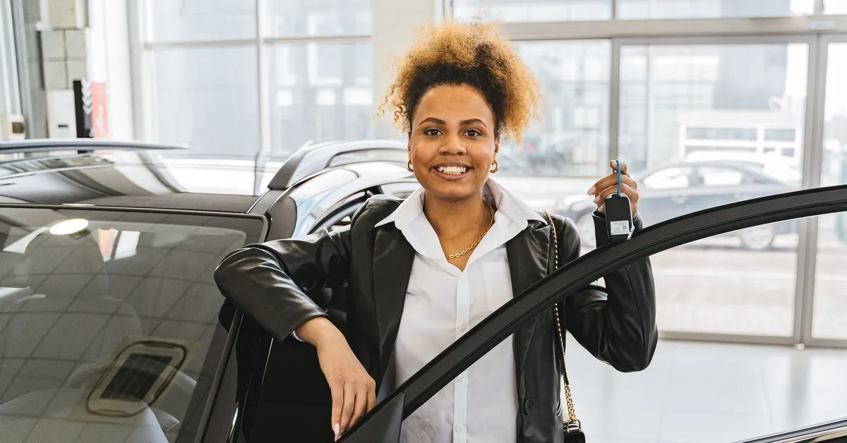 Frau mit Autoschlüssel am neuen Auto im Autohaus